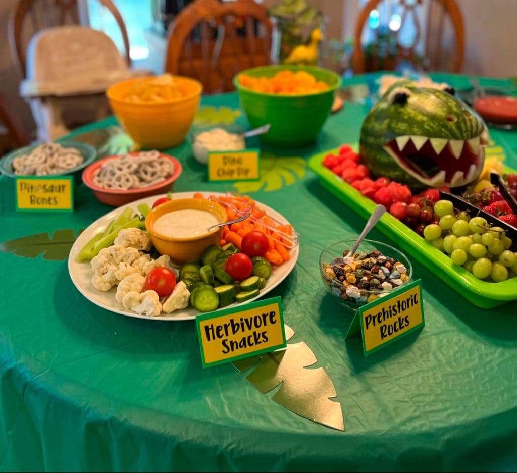 Best First and Second Birthday Party Ideas for Boys and Girls 104 Dinosaur-themed veggie and fruit platter labeled “Herbivore Snacks” with swamp dip for a dino party.