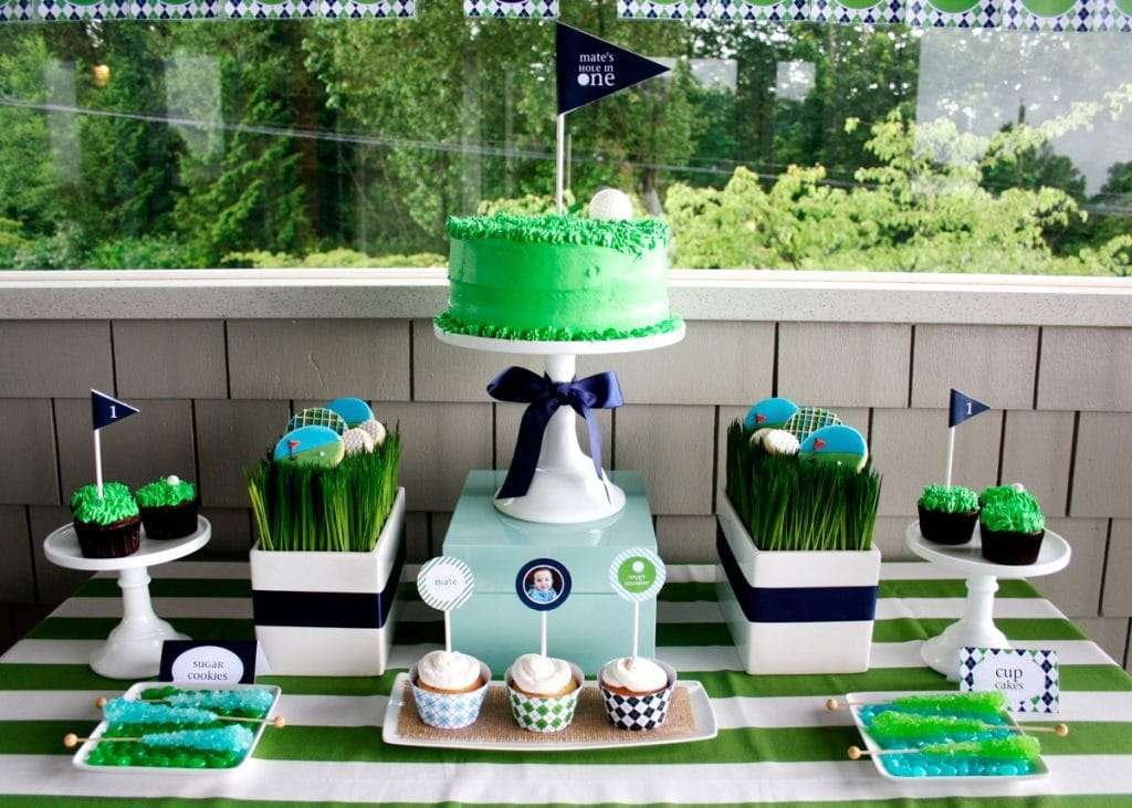 Best First and Second Birthday Party Ideas for Boys and Girls 14 Hole in One golf-themed birthday table with green cake, balloons, welcome sign, cupcakes, and golf ball decorations in a stylish setup.