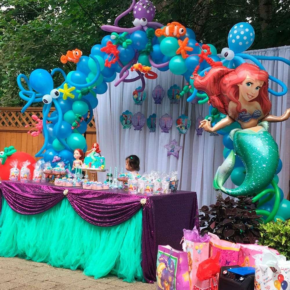 Best First and Second Birthday Party Ideas for Boys and Girls 71 Baby mermaid birthday party table setup with pastel balloons, seashell backdrop