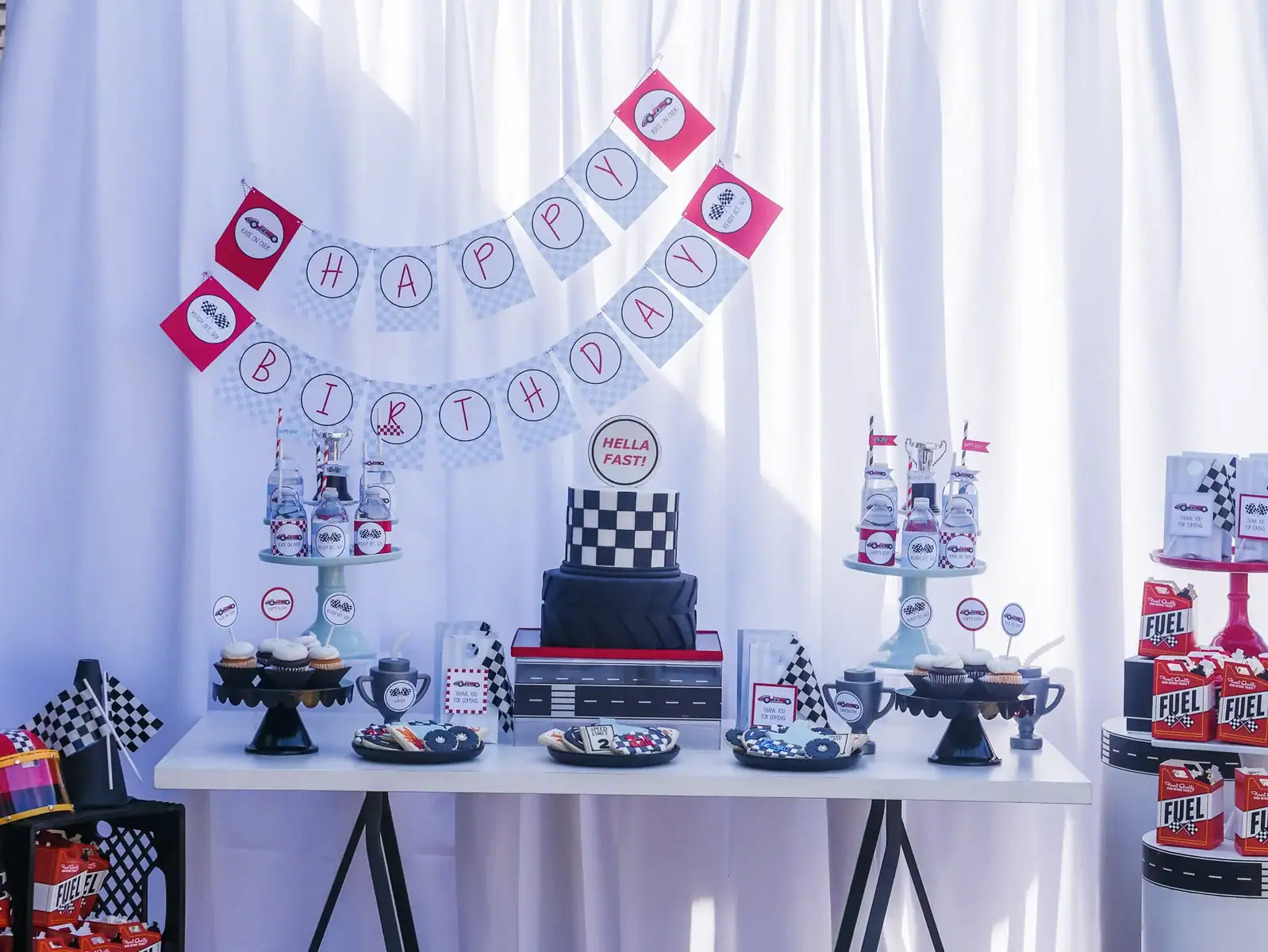 Race car themed dessert table with cupcakes, cake, and racing decorations