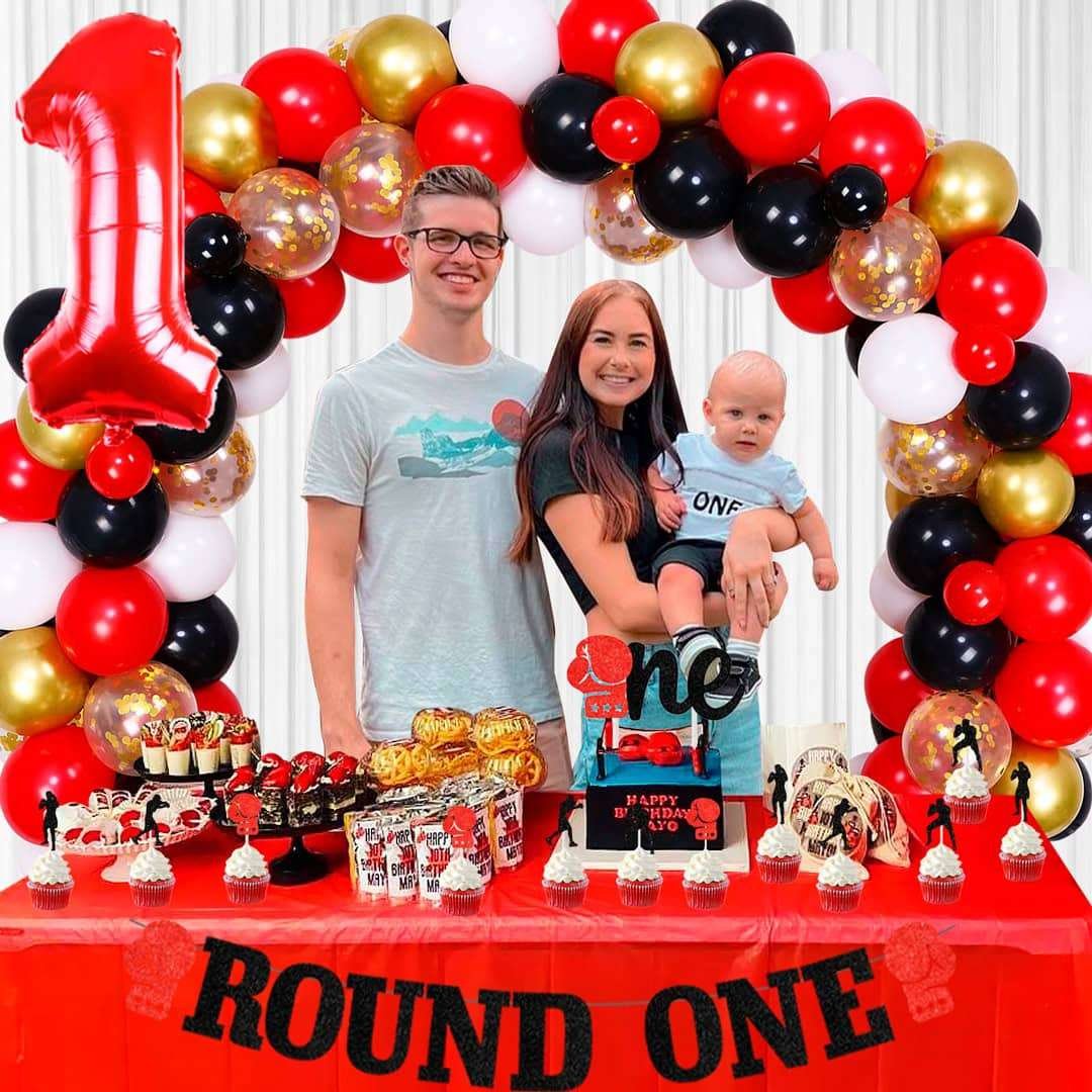 Best First and Second Birthday Party Ideas for Boys and Girls 3 Family celebrating a Round One boxing birthday party with red, black, and gold decorations, balloon arch, and themed desserts table.
